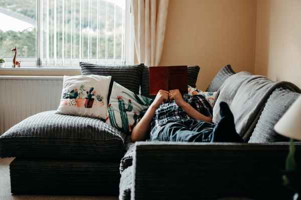 person lying on couch reading a book