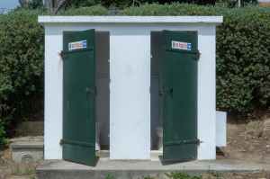 An Outside Toilet With Dark Green Doors