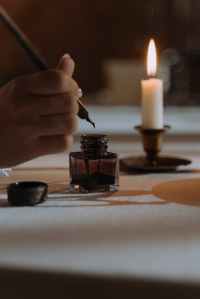 A Lit Candle And Quill Pen In Use